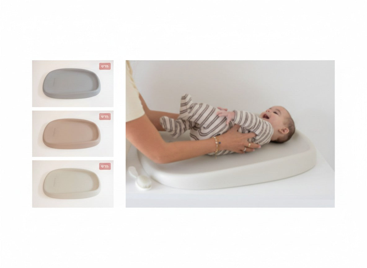 תינוק שוכב על משטח החתלה PU של בינה ובינו, ולצידו קטלוג צבעי הקולקציה: אפור (Grey), דאסטי רוז (Dusty Rose) ובז' (Beige).